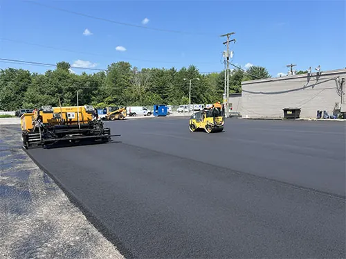 Asphalt Care Inc crew laying fresh pavement in a commercial parking lot